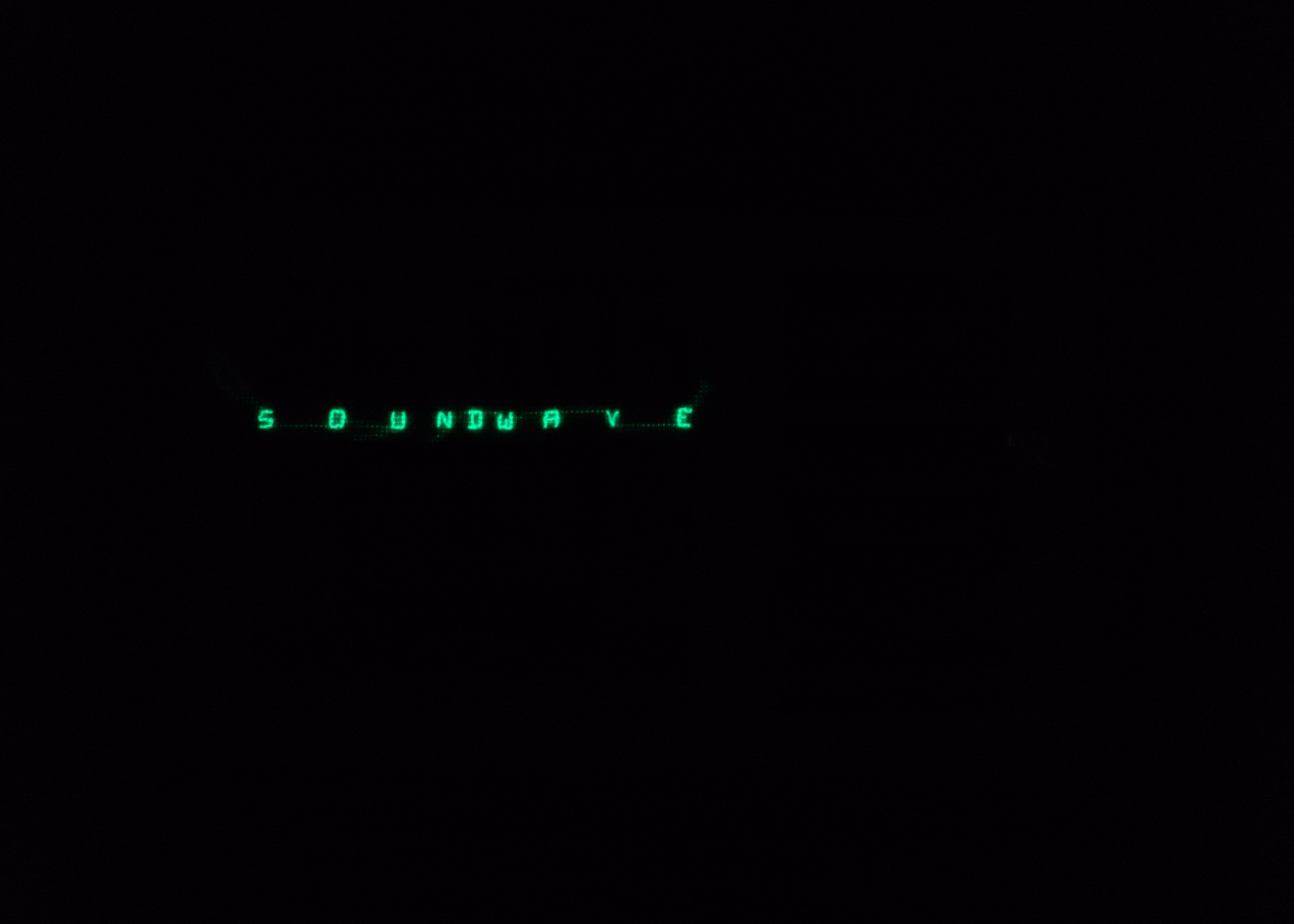 Glowing "SOUNDWAVE" on black Mostly black with the word SOUNDWAVE glowing where it would be on the actual piece.
